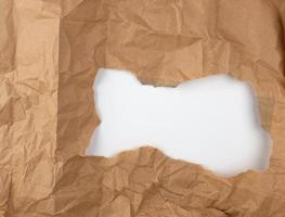 buraco redondo rasgado em papel pardo, fundo branco foto