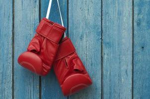 par de luvas de boxe penduradas em uma parede de madeira rústica foto