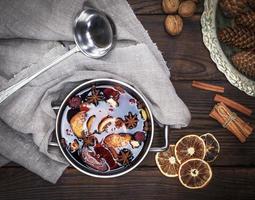 vinho quente com especiarias e pedaços de frutas em uma panela redonda de alumínio foto