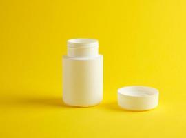 frasco de plástico branco aberto para medicamentos fica em um fundo amarelo foto