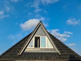 janela de telhado aberta em estilo velux com telhas pretas.