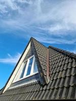 janela de telhado aberta em estilo velux com telhas pretas.