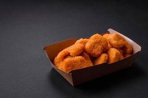 deliciosos nuggets de frango crocantes frescos em um fundo escuro de concreto foto