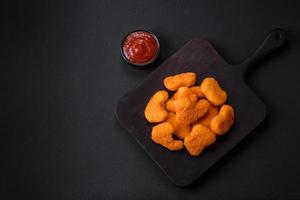 deliciosos nuggets de frango crocantes frescos em um fundo escuro de concreto foto