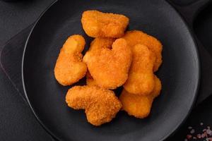 deliciosos nuggets de frango crocantes frescos em um fundo escuro de concreto foto