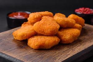 deliciosos nuggets de frango crocantes frescos em um fundo escuro de concreto foto