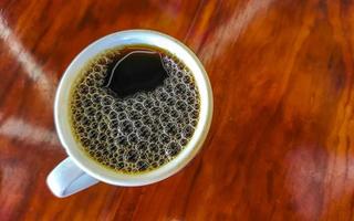 pote de xícara branca azul com mesa de madeira de café preto méxico. foto