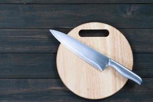 close-up faca de cozinha e tábua redonda de madeira foto