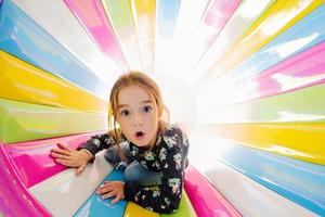 garota engraçada brincando no playground indoor play center em tubo colorido. foto