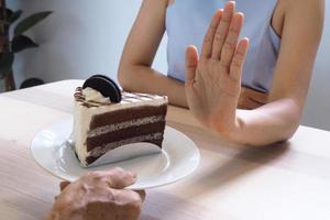 uma das moças do posto de saúde usou a mão para empurrar um prato de bolo de chocolate. recusar-se a comer alimentos que contenham gordura trans. foto