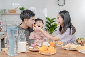 atividades juntos durante as férias. pais e filhos estão fazendo uma refeição juntos durante as férias. menino está provocando seu pai, dando-lhe pão e legumes. foto