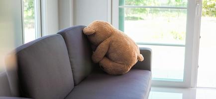 conceito de criança de tristeza. ursinho de pelúcia sentado encostado na parede da casa sozinho, parece triste e desapontado. foto
