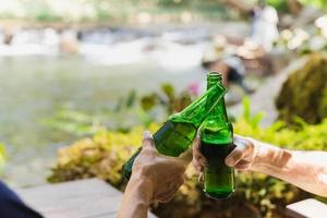 homem sênior brindando com cerveja de garrafa junto com seu filho de férias. foto
