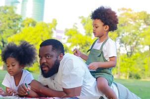 família feliz em deitar-se no gramado do parque juntos de férias. conceito de amor e laços familiares foto