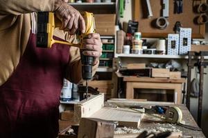 carpinteiro com uma broca amarela fazendo um furo com uma broca de madeira a bordo foto