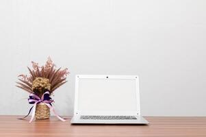 laptop e vaso de flores na mesa foto