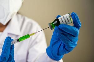 cientistas usando máscaras e luvas segurando uma seringa com uma vacina covid-19 foto
