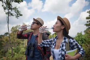 jovens caminhantes bebendo água na floresta foto