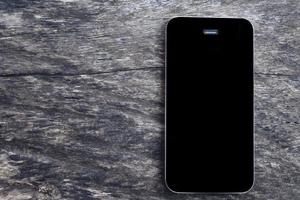 vista superior do smartphone móvel maquete de tela preta no fundo da mesa de madeira velha em branco. vista aérea plana leigos e cópia espaço para o conceito de negócio. foto