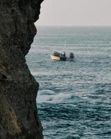 barco branco no mar ao lado da formação rochosa marrom durante o dia foto