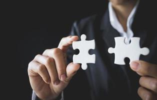 duas mãos do empresário para conectar a peça do quebra-cabeça de casal. símbolo de associação e conexão. estratégia de negócio. foto