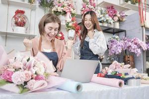 duas jovens e belas parceiras floristas surpreendem com o pedido de compra do cliente no site de comércio eletrônico, empresário de negócios bem-sucedido, trabalho feliz em floricultura, loja online de buquê de flora colorida. foto