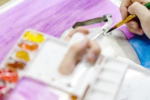 closeup mãos segurando pincel e paleta colorida com tintas aquarela por pintura de artista foto