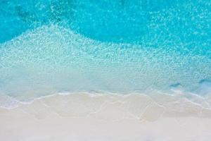 verão seascape belas ondas, água do mar azul em um dia ensolarado. vista superior do drone. vista aérea do mar, incrível fundo de natureza tropical. belo mar brilhante com ondas espirrando e conceito de areia de praia foto