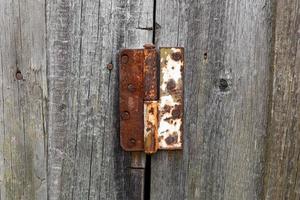 velha dobradiça de porta de metal enferrujado. dobradiça de porta em uma porta de madeira. foto
