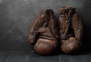 luvas de boxe vintage de couro marrom em um fundo preto foto