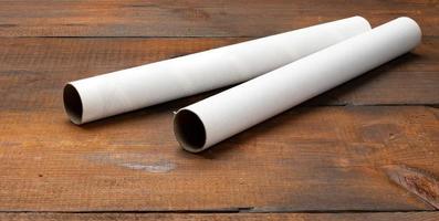 tubo de papel branco de um rolo de toalhas de cozinha, objeto em um fundo de madeira marrom foto