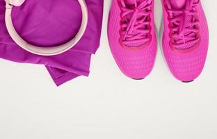 par de tênis esportivos roxos têxteis, fones de ouvido sem fio em um fundo branco foto