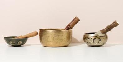 tigela de canto de cobre e badalo de madeira em uma mesa branca. instrumento musical para meditação, relaxamento, várias práticas médicas relacionadas com biorritmos, normalização da saúde mental foto