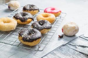 rosquinhas de chocolate e rosquinhas rosa na mesa da cozinha foto