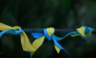 fita de seda azul e amarela amarrada em um tubo de metal. símbolo da bandeira ucraniana, luta pela independência foto