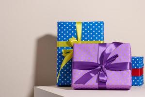 caixa embalada em papel roxo festivo e amarrada com fita de seda sobre fundo bege, presente de aniversário, surpresa foto