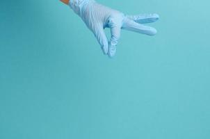 a mão do médico em uma luva médica azul segura um objeto em um fundo azul foto
