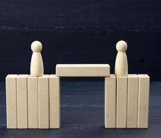figuras de madeira de homens em uma ponte feita de blocos. o conceito de uma disputa entre oponentes, diálogo foto