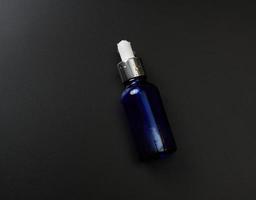 pipeta de garrafa de vidro em um fundo preto. conceito de farmácia. pele de colágeno. maquete de produto cosmético para cuidados com a pele foto