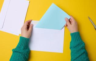 mão feminina segura envelopes de papel branco em um fundo laranja, vista superior. enviar e receber correspondência foto