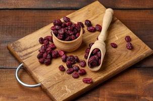 bando de cranberries secas em uma colher de pau em uma mesa marrom. baga deliciosa, vista superior foto