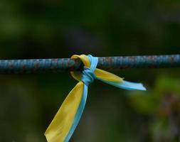 fita de seda azul e amarela amarrada em um tubo de metal. símbolo da bandeira ucraniana, luta pela independência foto