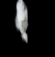 nuvem de farinha de trigo branca sobre um fundo preto, partículas voam em diferentes direções foto