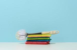 esponja e escova de plástico com alça para limpar a casa em um fundo azul foto
