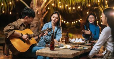 retrato de grupo asiático feliz de amigos se divertindo com música jantando e bebendo juntos ao ar livre - grupo de amigos felizes brindando cervejas - pessoas, comida, estilo de vida de bebida, conceito de celebração de ano novo. foto