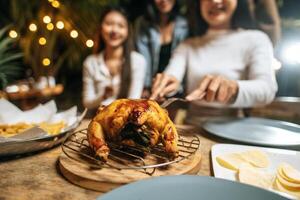 amigos asiáticos felizes torcendo com jantar de peru assado ao ar livre - grupo de pessoas se divertindo na festa de ano novo. pessoas, comida e bebida conceito de estilo de vida festa noturna, pessoas e conceito de celebração. foto