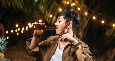 retrato de um homem asiático feliz jantando - jovens sentados na mesa do bar brindando ao jantar com copos de cerveja ao ar livre - pessoas, comida, estilo de vida de bebida, conceito de celebração de ano novo. foto