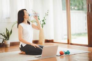 mulher bebendo água enquanto faz exercícios virtuais foto