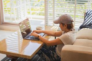 mulher usando laptop enquanto está sentado no chão da sala de estar. foto