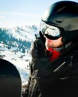homem em equipamento de esqui, usando óculos de segurança, falando em walkie-talkie. procurando pó para freeride foto
